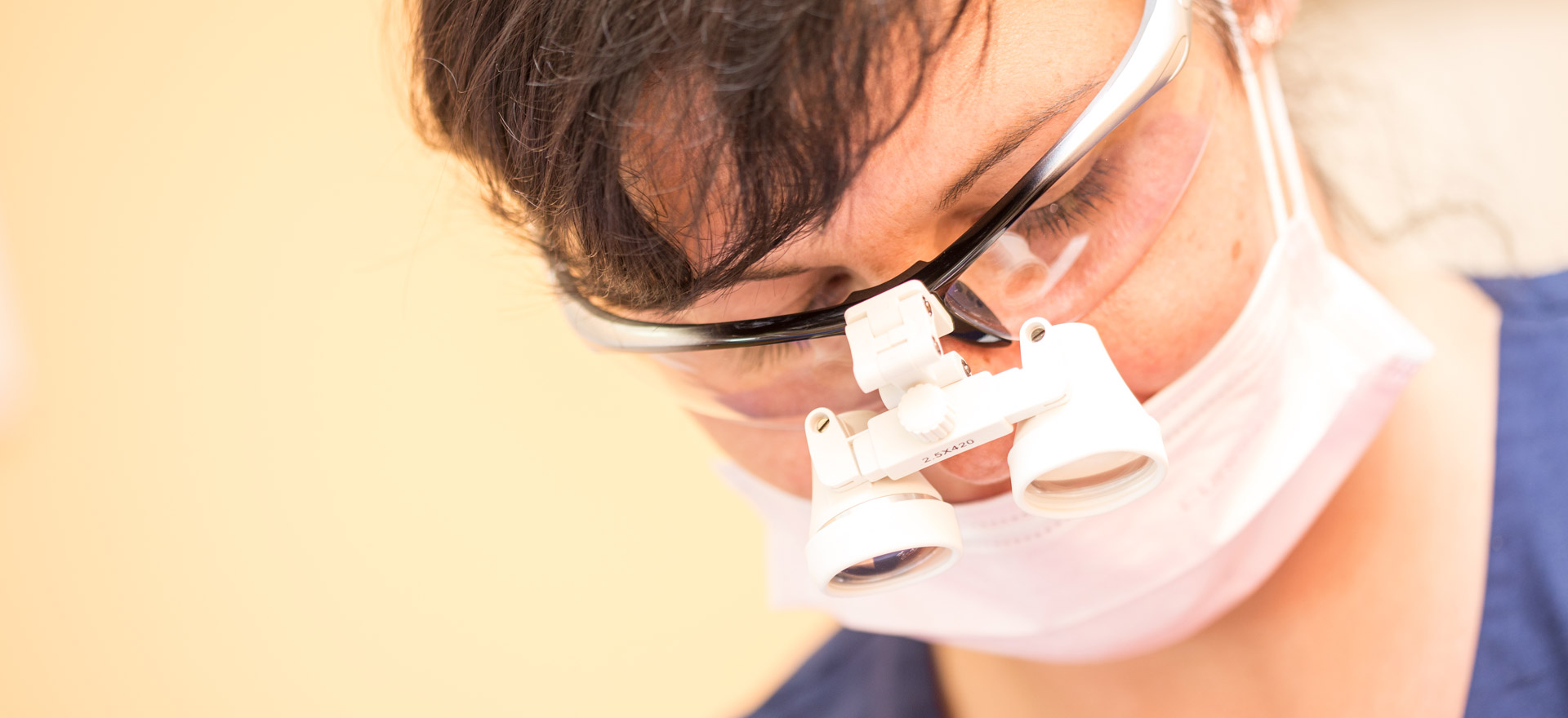 Dentalhygienikerin mit Lupenbrille führt chirurgische Parodontosebehandlung durch.